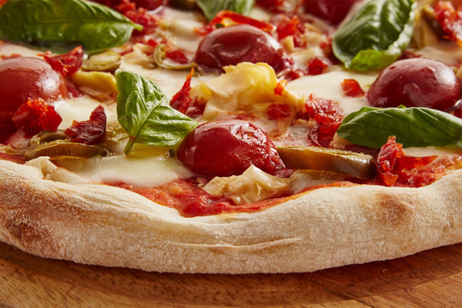 Frisch gebackene Pizza mit Tomaten, Käse und Basilikum in Nahaufnahme